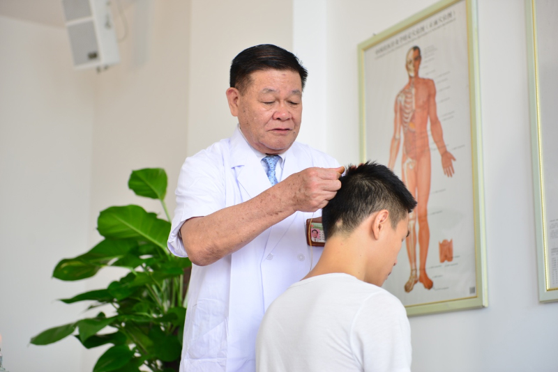 国医大师黄瑾明为患者进行壮医药线点灸疗法治疗。beat365平台官方网站供图